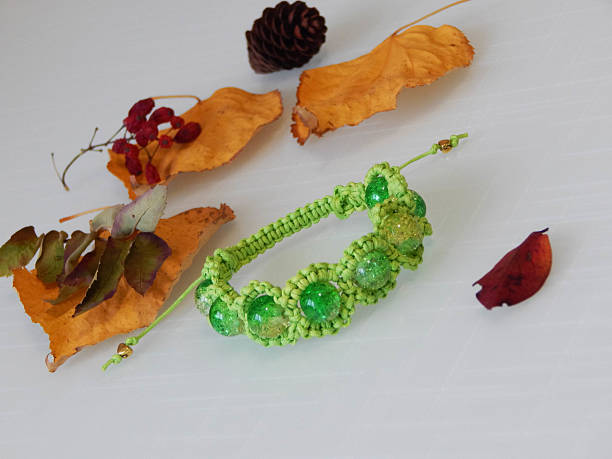 Green bracelet and yellow leafs. Green friendship bracelet on a white