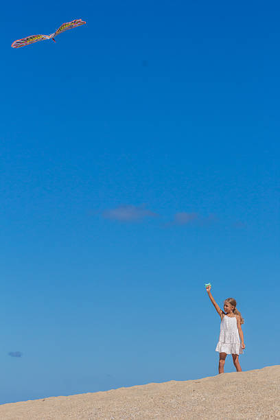 istock Child gripping a kite on the sandy shore 2228601425