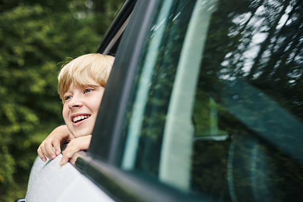 istock Caucasian Child Boy Smiling While Looking out Car Window during Road Trip 2228601769