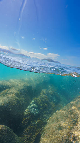 istock Underwater reef with rocks and surface view of sky and clouds 2228602362