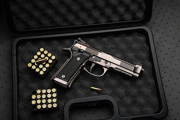istock A silver pistol and golden ammo in a black hard case with protective foam. 2228606904