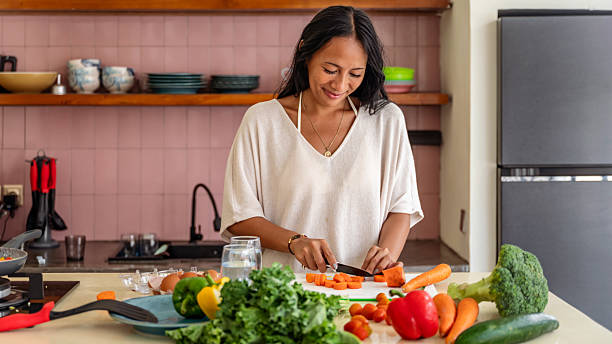 istock Smiling Woman Chopping Fresh Vegetables in a Cozy Home Kitchen Environment 2228608042