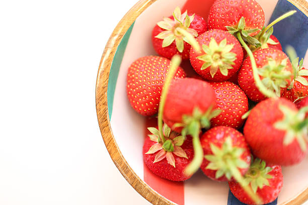 Fresh strawberries in a colourful bowl shot on a white background
