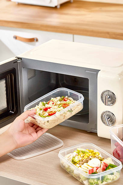istock Heating Leftovers in Microwave Using Plastic Food Containers, Man taking out a healthy lunch from a toaster in the kitchen 2228611967