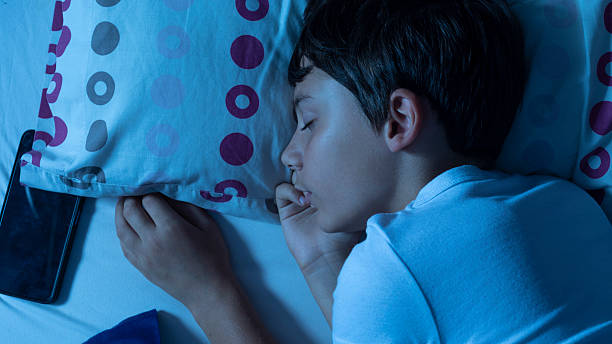 istock Child sleeping with smartphone next to pillow at night 2228612218