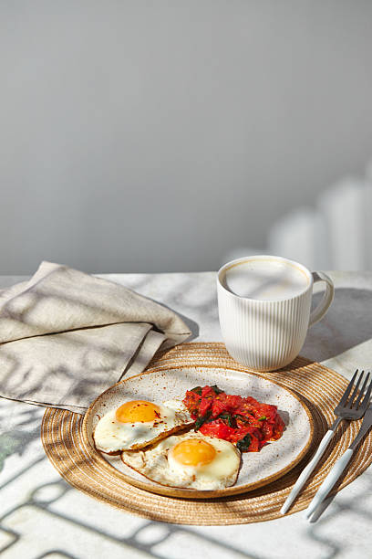 istock Breakfast with fried eggs and fried tomatoes with spinach on plate and cup of latte coffee 2228616604