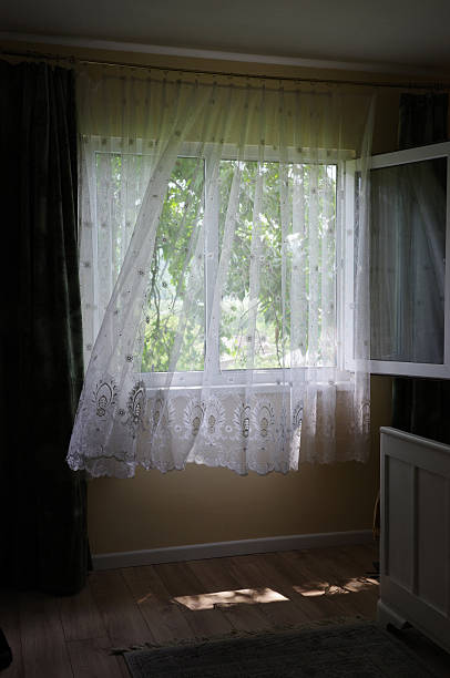 Sunlight streams through a window, illuminating the soft white curtains in a peaceful room.