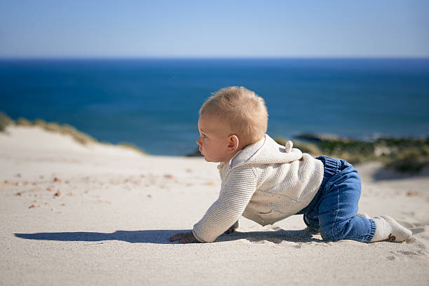 istock Cute Baby Crawling in Sand with Ocean in Background 2228629881