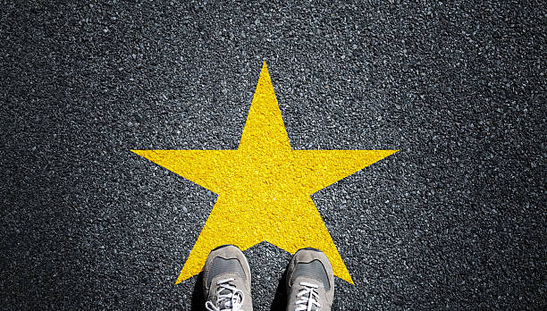 istock Feet on asphalt road with a yellow star 2228630394