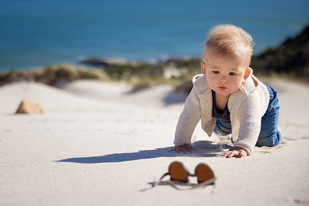 An abandoned child shoe lying on a sandy beach, representing marine debris, ocean pollution, and the impact of human waste on coastal environments.