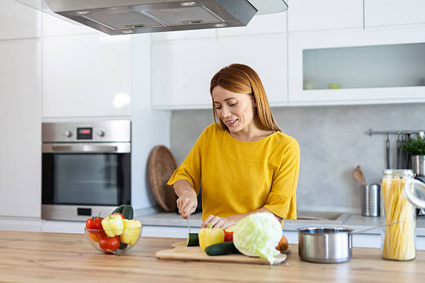 istock Smiling Woman Chopping Vegetables in Bright Kitchen 2228634052