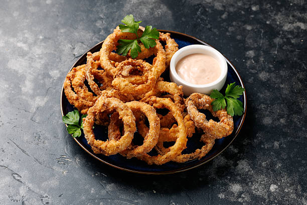 istock Homemade deep fried onion rings on plate with sauce. 2228639108