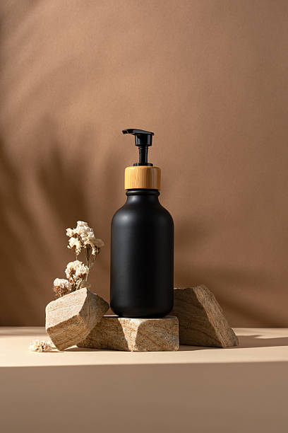 istock Minimal black cosmetic bottle mockup with bamboo pump cap on stone podium 2228639571