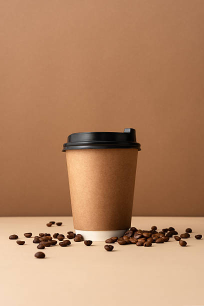 istock Paper coffee cup with black plastic lid and scattered coffee beans 2228640497