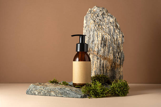 istock Minimal amber cosmetic bottle mockup with pump and blank kraft label on stone podium 2228640558