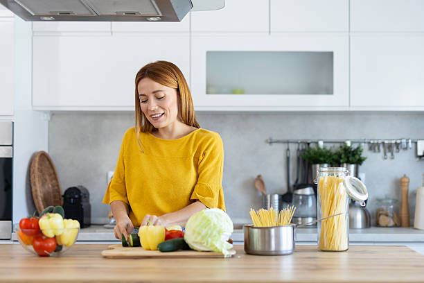 istock Joyful Woman Cooking Fresh Ingredients in Bright Kitchen 2228640771