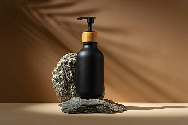 istock Minimal black cosmetic bottle mockup with bamboo pump cap on stone podium 2228640887