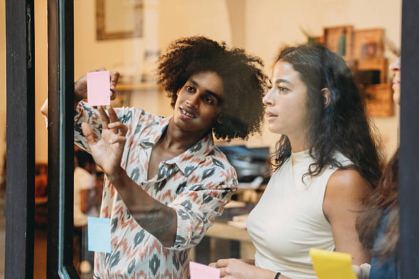 istock Young Professionals Brainstorming with Sticky Notes on Glass Wall 2228651012