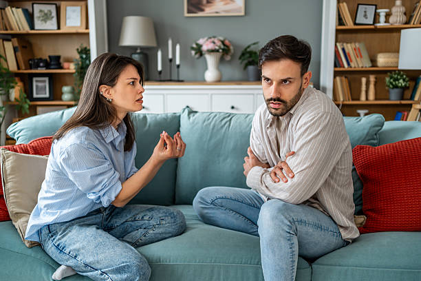 istock Young couple arguing while sitting on sofa at home 2228653884