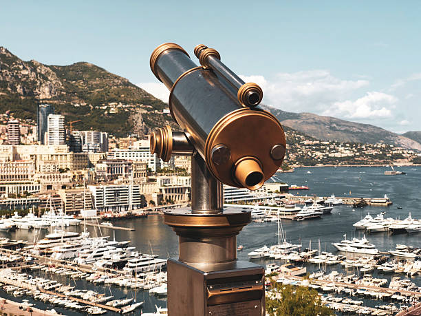 Vintage brass telescope on the side of a harbour with yachts in the background