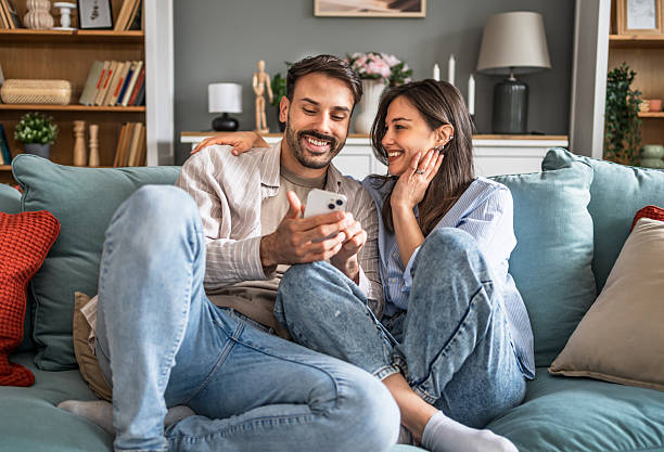 istock Happy young couple relaxing at home and browsing smartphone together 2228654029
