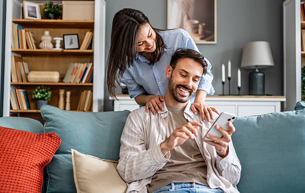 istock Happy young couple relaxing at home browsing smartphone 2228654147