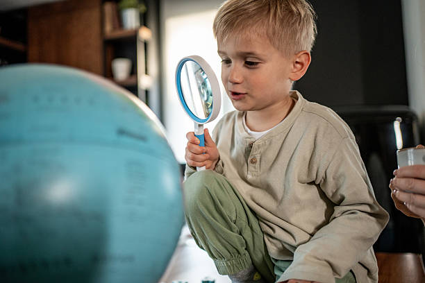 istock Curious child exploring world with magnifying glass at home 2228654751