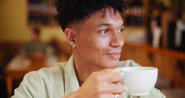istock Man, coffee and happy with thinking at cafe for memory, drink and relax with inspiration at restaurant. Person, smile and tea cup with reflection, remember and perspective with beverage at diner 2228656174