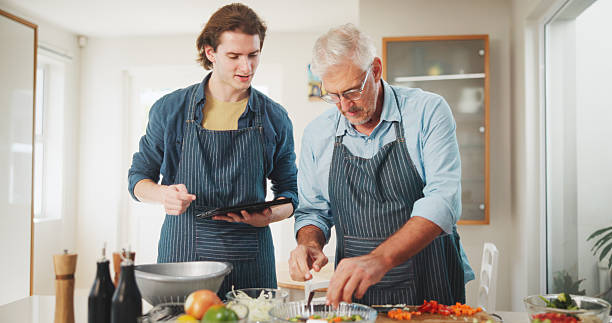 istock Men, chef or cooking with tablet in kitchen for culinary skill or hospitality in home. Mature, mentor and helping person with technology or ingredients for meal prep, house recipe or food cuisine 2228656596