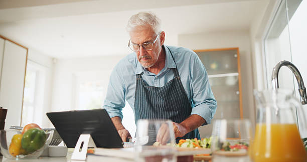 istock Learning, senior or man with tablet for cooking recipe tutorial, lunch and guide in home. Kitchen, retirement or elderly person reading blog for ingredients instruction, food diet or meal prep steps 2228656623