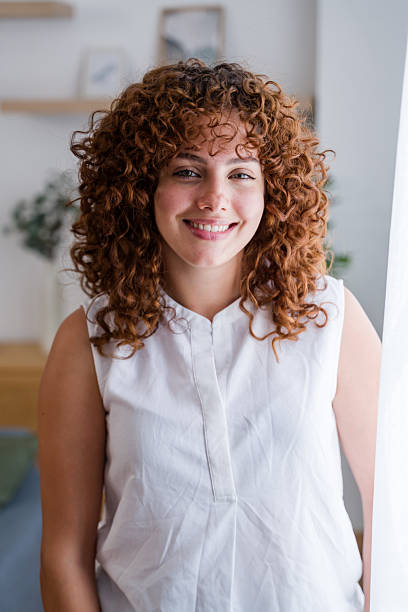 istock Young woman with curly red hair smiling at home 2228659270