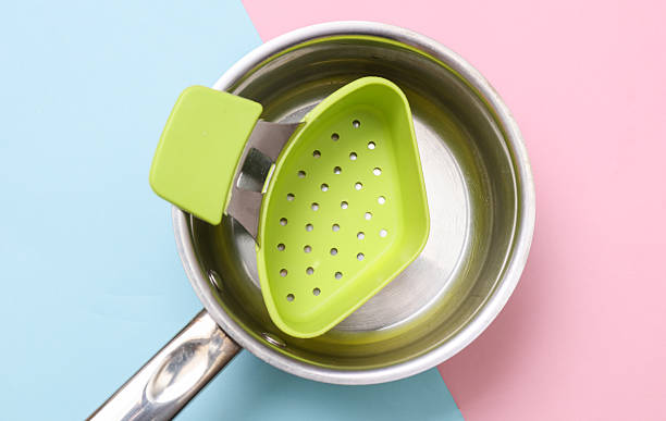 Saucepan with colander on blue pink background. Top view