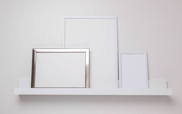istock Shelf with white empty photo frames on the wall. Mockup for design 2228666929