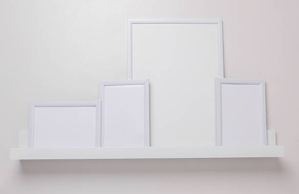 istock Shelf with empty photo frames on white wall. Mockup for design 2228666957