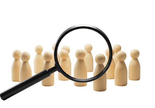 istock Isolated Magnifying Glass Highlighting Wood Figure in Crowd 2228667599