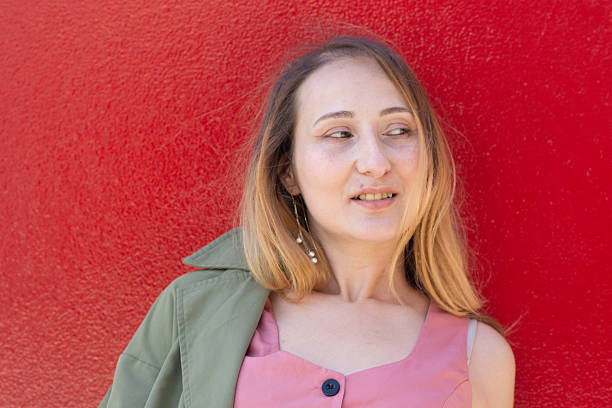 istock Young woman posing with light colored clothes against a red wall 2228669309