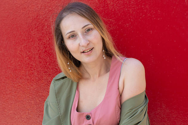 istock Young woman smiling and posing against a red wall 2228669407