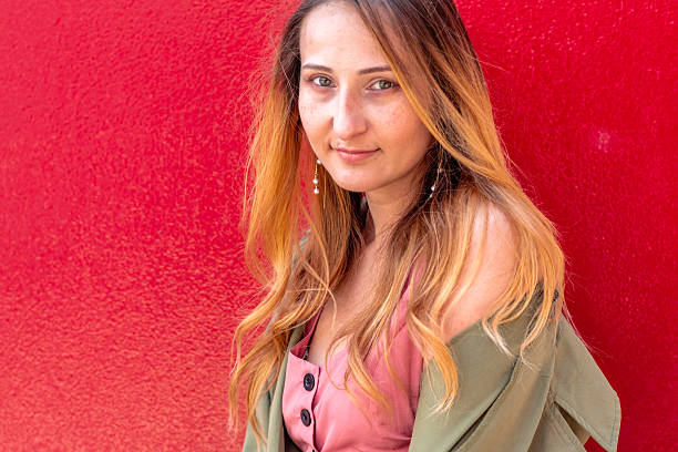istock Young woman posing against a vibrant red wall 2228669427
