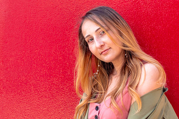 istock Young woman posing with red wall background in autumn setting 2228669451