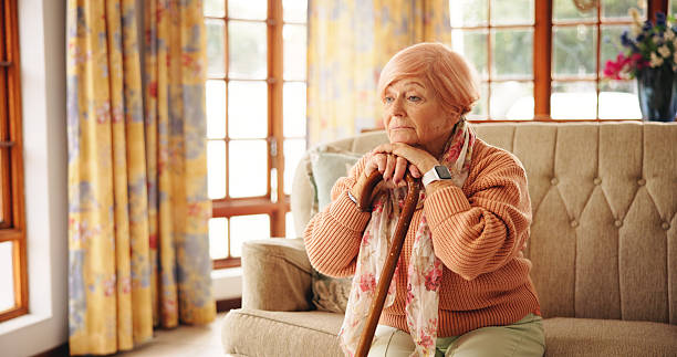 istock Walking stick, memory and senior woman in home with thinking, retirement or remember nostalgia. Ideas, wood cane and elderly female person with a disability on sofa with daydreaming in house. 2228676665