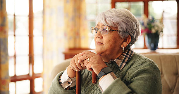 istock Walking stick, thinking and senior woman in home with nostalgia, retirement or remember memory. Ideas, wood cane and elderly female person with a disability on sofa with daydreaming in house. 2228676743