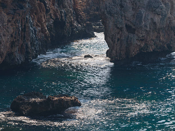 Crete, Greece coastal path along rugged cliffs at sunset. A serene Mediterranean landscape with rocky terrain, low vegetation, and a calm sea to the left. Perfect for travel, nature, hiking, and scenic imagery celebrating coastal beauty and peaceful sunset moments in Greece.