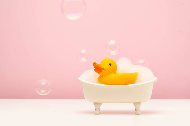 istock Cute miniature bathtub with foam and yellow rubber duck, surrounded by floating bubbles on a soft pink background. Fun and whimsical bathroom or childhood concept. 2228681241