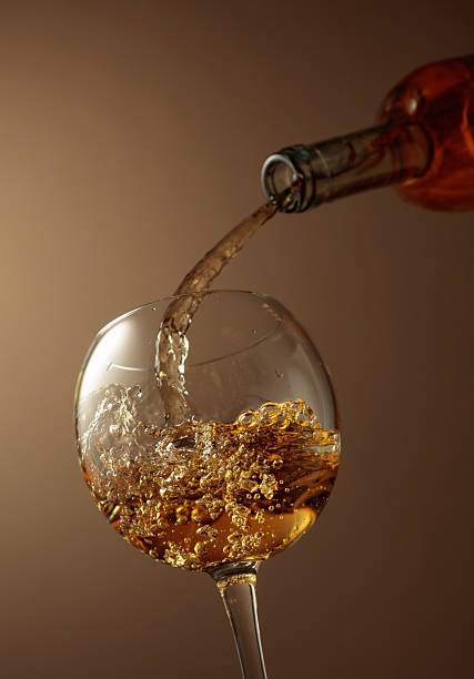 istock Pouring white wine from a bottle into a glass. 2228684375