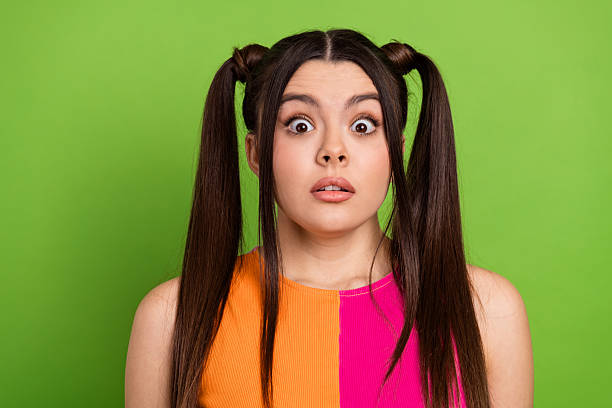 istock Charming young woman with surprised expression posing against vibrant green background showcasing stylish hairstyle 2228685050