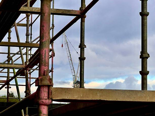 Scaffolding with a crane in the background against cloudscape