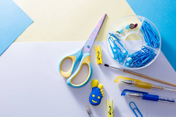 Bright school and office supplies including scissors, pens, pencils, sticky notes, paper clips, and markers scattered on a white surface.