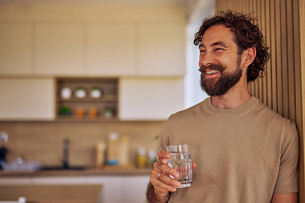 istock Smiling man drinking water in his modern kitchen 2228688864