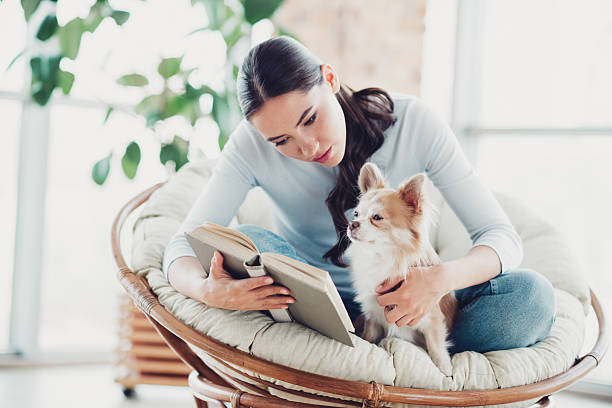 istock Young woman reading a book and spending time with dog in a cozy home setting 2228689054