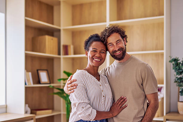 istock Happy multi-ethnic couple embracing at home, smiling and looking at camera 2228689108